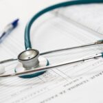 Estetoscópio sobre formulários e documentos médicos, representando os documentos necessários para conseguir uma liminar contra o plano de saúde